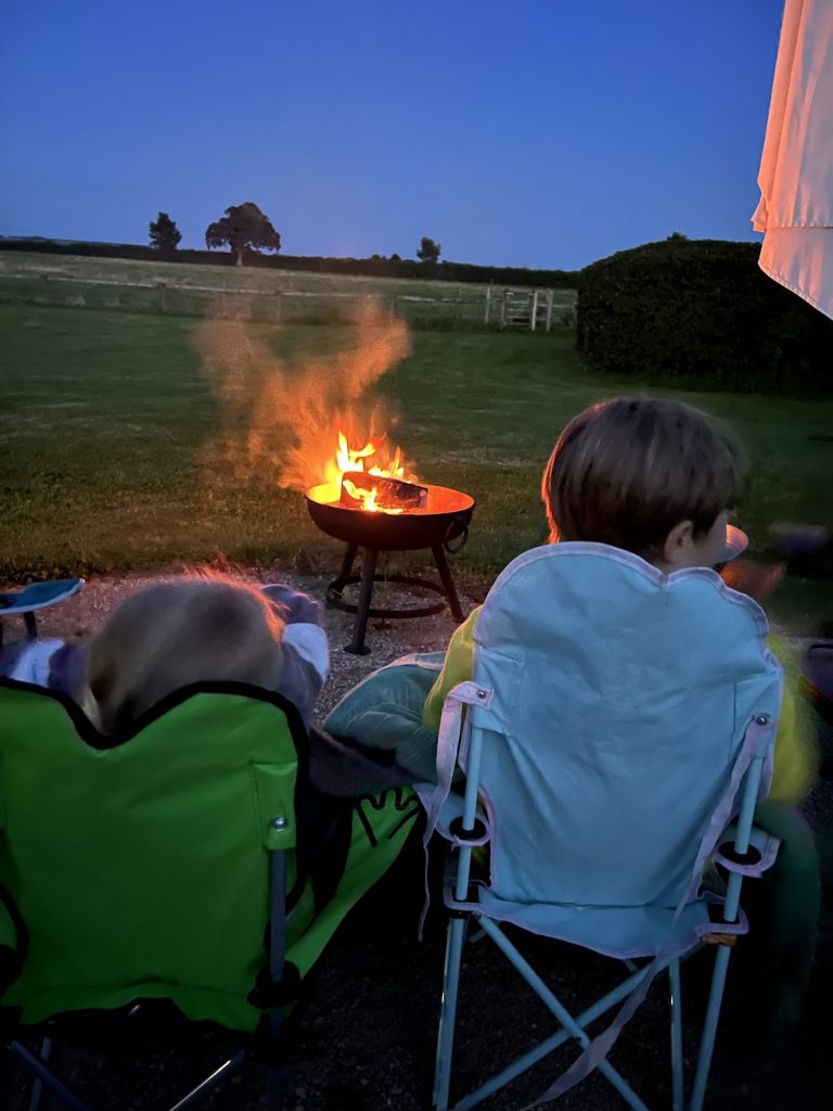 Children facing away from the camera towards a camp fire